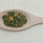 a wooden spoon filled with green tea on top of a table