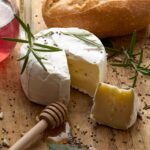 Cheese, bread, and honey on a wooden board.