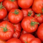 A pile of ripe red tomatoes with green stems.